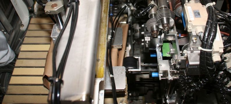 compacte IAI elektrische actuator (rechts bovenin) voor de beweging van de rol voor het dichttapen van de verpakking is ingebouwd in een krappe ruimte